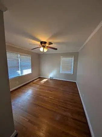 an empty room with wooden floor chandelier fan and windows