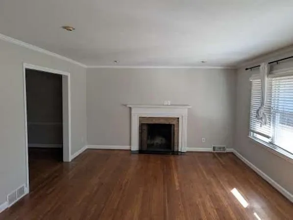 an empty room with wooden floor a fireplace and windows