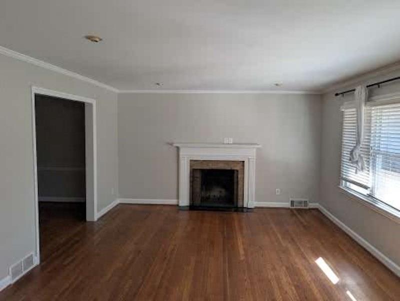 1216 Beech Haven Road Northeast Atlanta, GA 30324 - Photo 4 of 18 an empty room with wooden floor a fireplace and windows