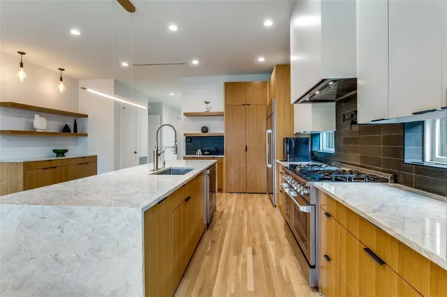 a large kitchen with stainless steel appliances granite countertop a large stove top oven a sink dishwasher and a refrigerator with wooden floor