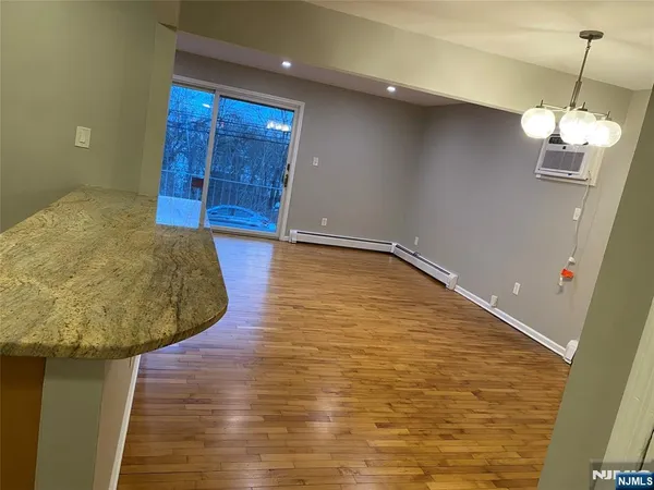 a view of a livingroom with wooden floor and kitchen space