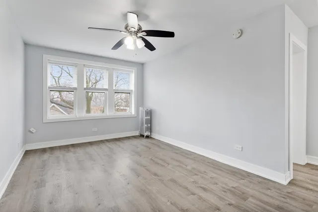 an empty room with wooden floor fan and windows