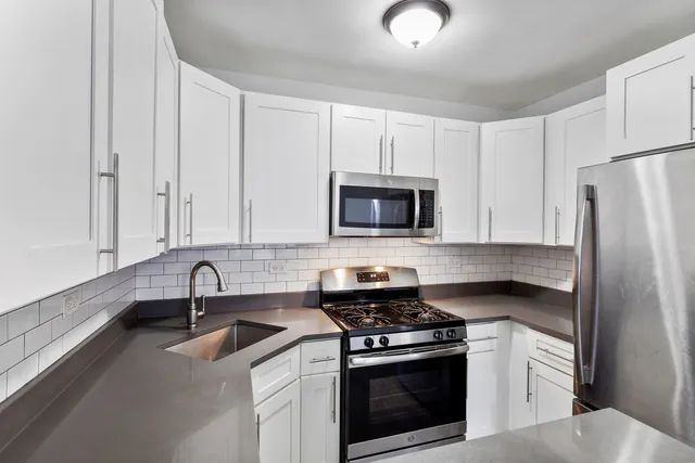 a kitchen with white cabinets and stainless steel appliances