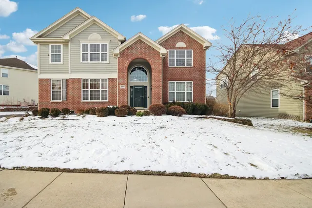 a front view of a house with a yard covered with snow