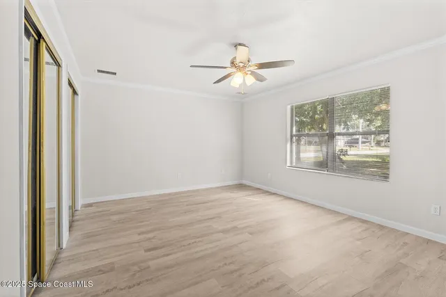 a view of empty room with wooden floor and fan