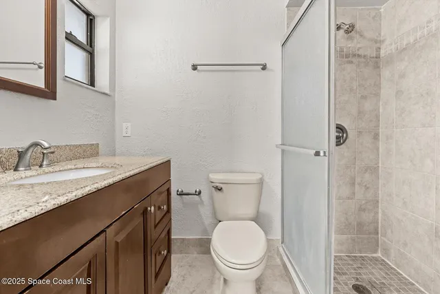 a bathroom with a granite countertop sink toilet and shower