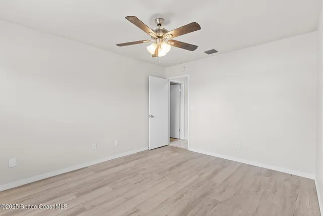 an empty room with wooden floor and ceiling fan