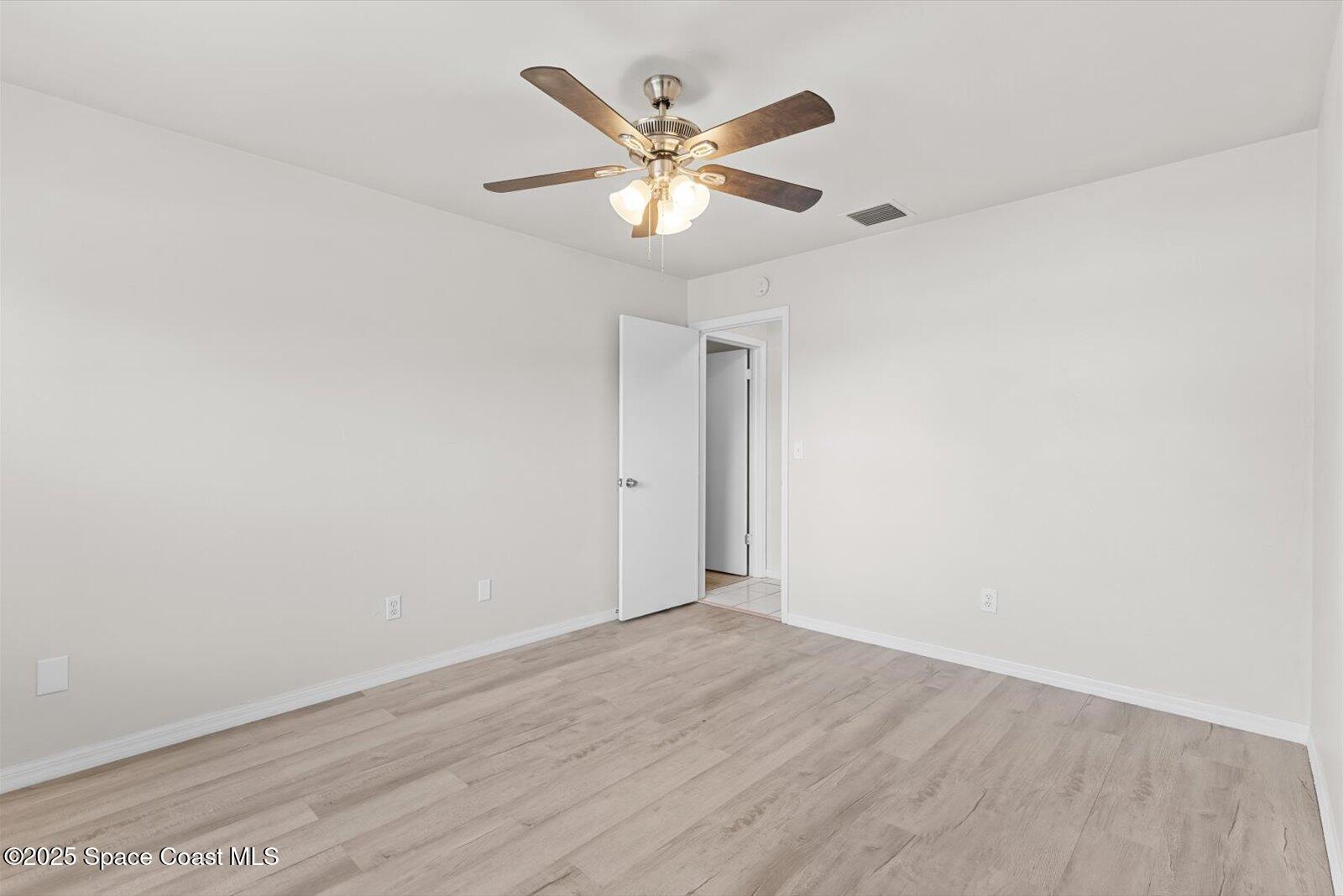 402 Southwest Sansom Lane Port St. Lucie, FL 34953 - Photo 21 of 33 an empty room with wooden floor and ceiling fan