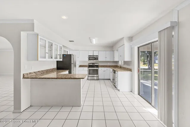 a kitchen with stainless steel appliances kitchen island granite countertop a refrigerator and a sink