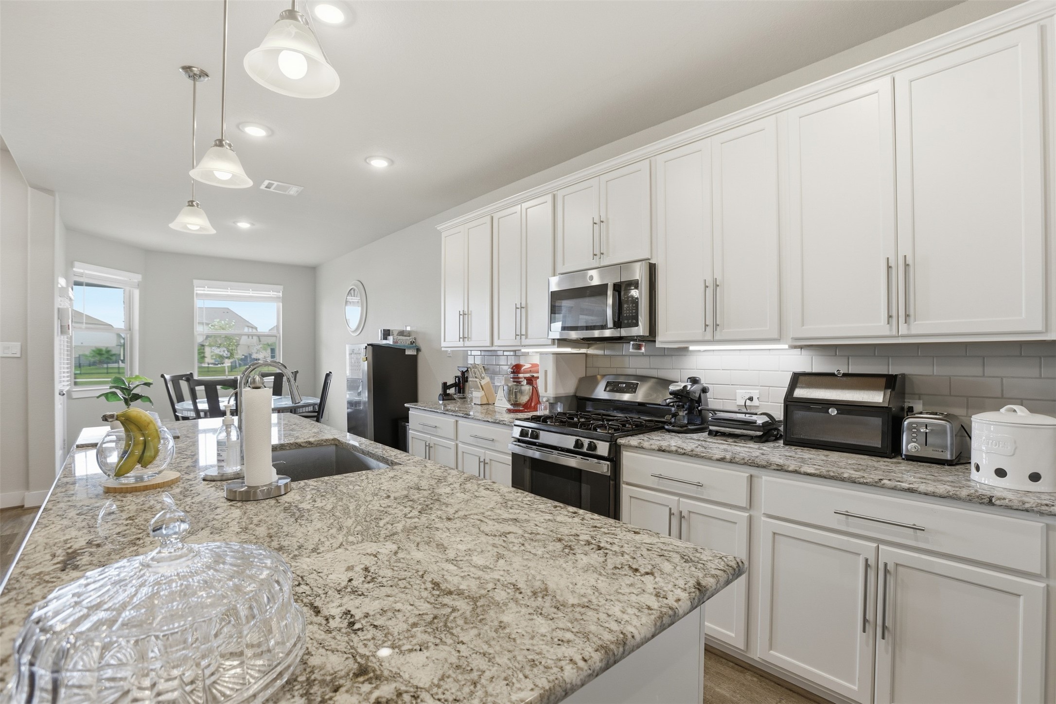 2725 Arbor Edge Crossing La Marque, TX 77568 - Photo 11 of 38 a kitchen with stainless steel appliances granite countertop a stove top oven a sink a stove a dining table and chairs with white cabinets