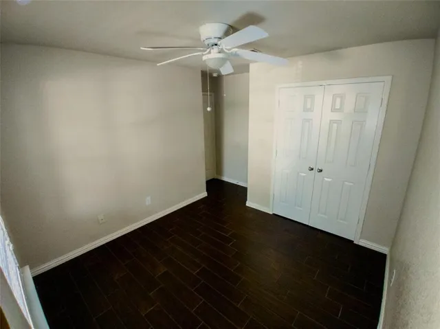 an empty room with wooden floor and fan
