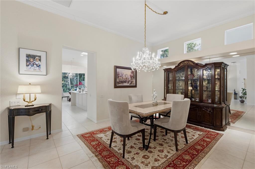 3033 Olde Cove Way Naples, FL 34119 - Photo 22 of 49 Dining area featuring light tile patterned flooring, ornamental molding, and a chandelier