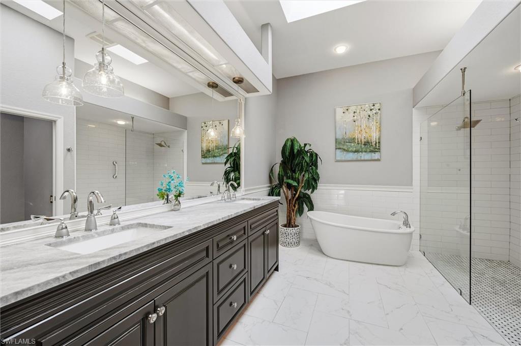 3033 Olde Cove Way Naples, FL 34119 - Photo 28 of 49 Bathroom with tiled shower, a skylight, double vanity, a soaking tub, and walk-in shower and private toilet area