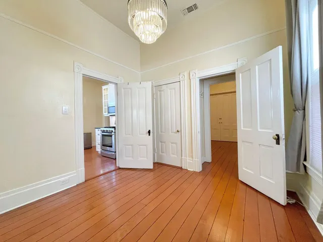an empty room with wooden floor and a hallway