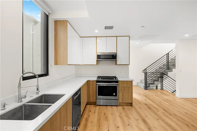 a kitchen with stainless steel appliances granite countertop a sink a stove and a wooden floors