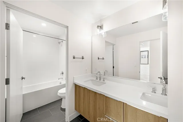 a bathroom with a double vanity sink a mirror and a bathtub