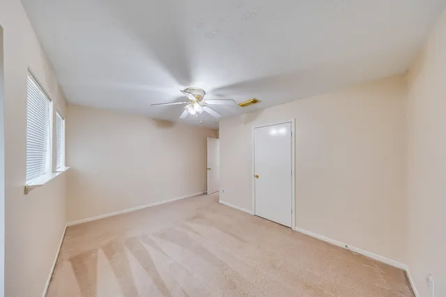 a view of an empty room with chandelier fan and a window