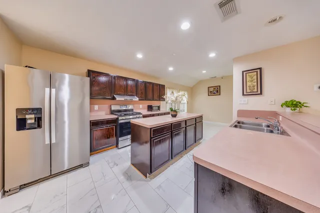 a kitchen with stainless steel appliances kitchen island granite countertop a refrigerator and a stove top oven