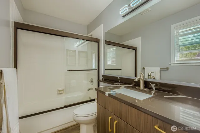 a bathroom with a granite countertop sink toilet and shower