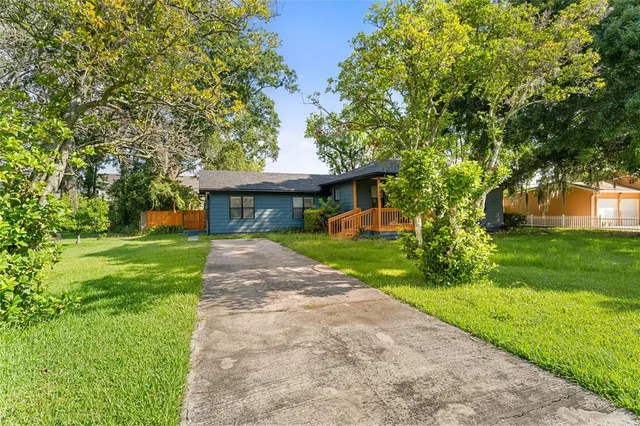 a front view of a house with a garden and trees