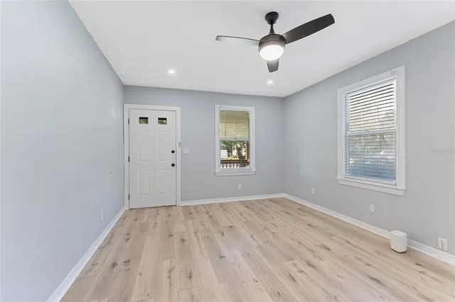 an empty room with wooden floor and windows