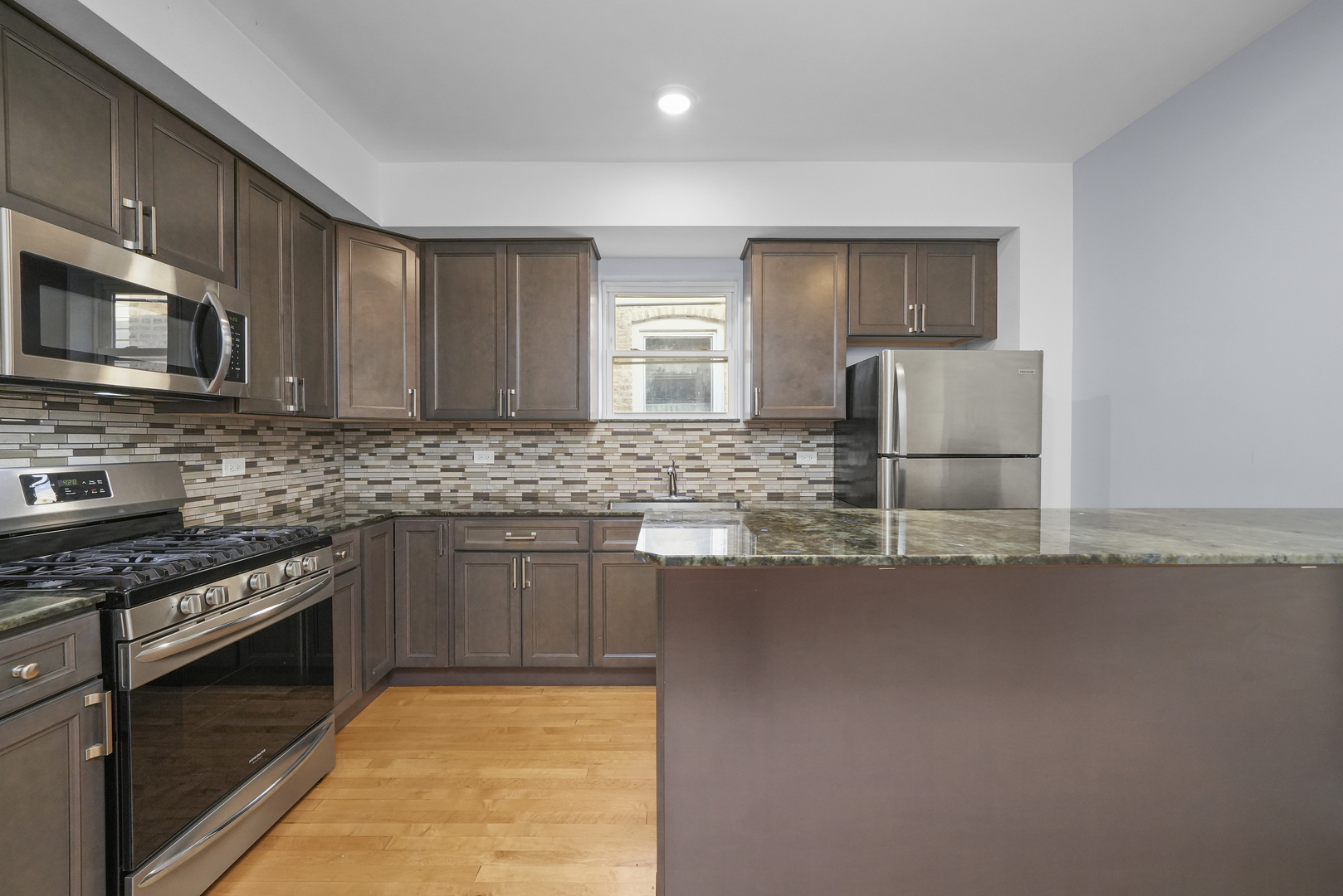 4239 West Melrose Street, Unit 2 Chicago, IL 60641 - Photo 20 of 27 a kitchen with stainless steel appliances granite countertop a stove a sink and a microwave