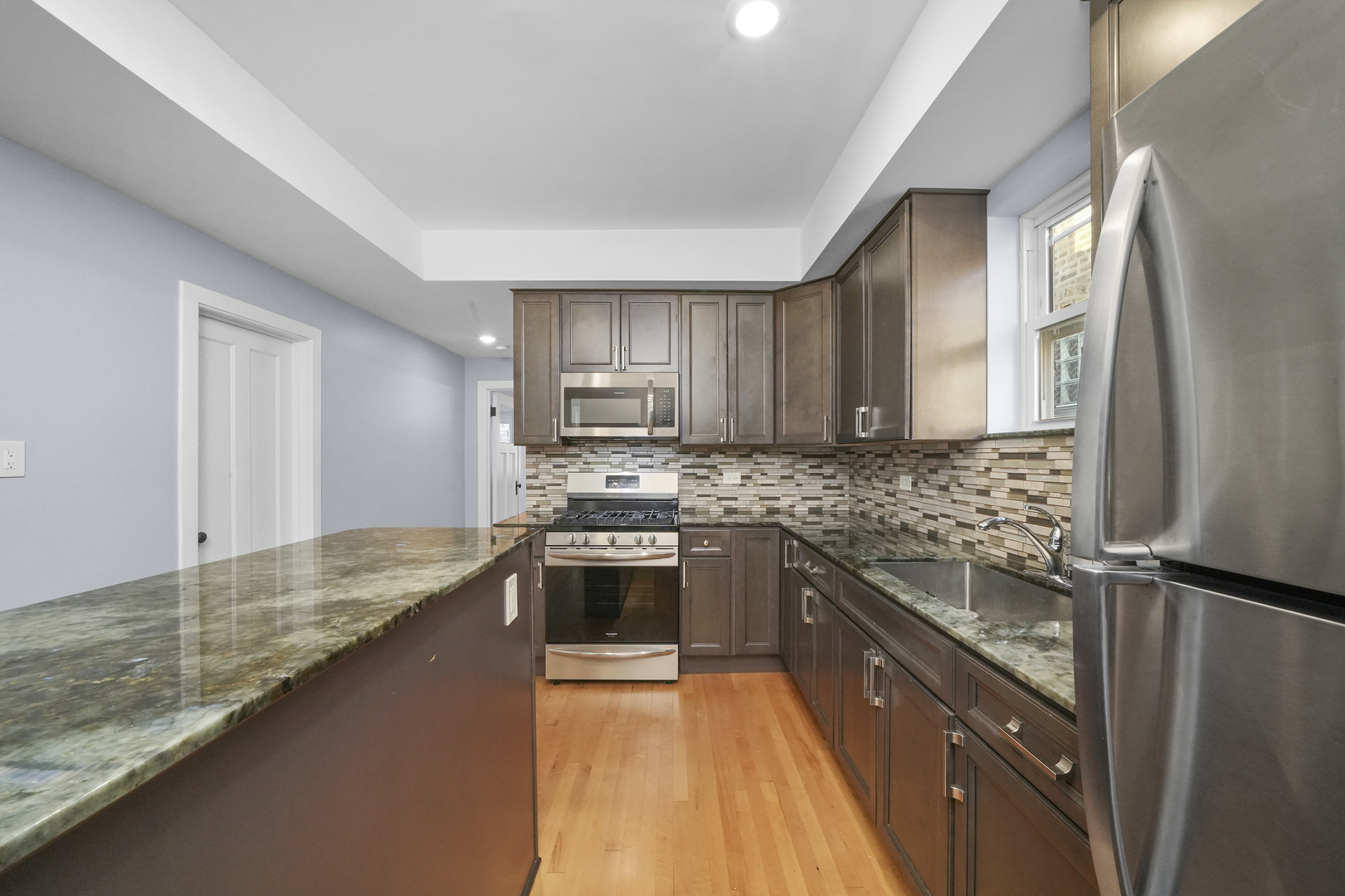 4239 West Melrose Street, Unit 2 Chicago, IL 60641 - Photo 23 of 27 a large kitchen with granite countertop a sink and stainless steel appliances