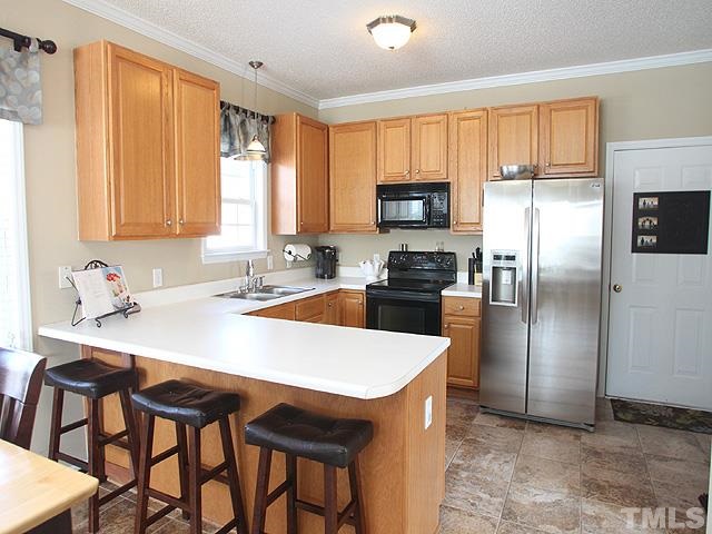 4908 Topstone Road Raleigh, NC 27603 - Photo 3 of 14 a kitchen with stainless steel appliances granite countertop a stove a refrigerator a sink a table and chairs