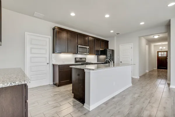 a kitchen with kitchen island granite countertop a refrigerator and a sink