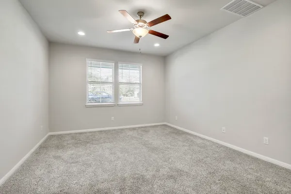 an empty room with windows and a fan