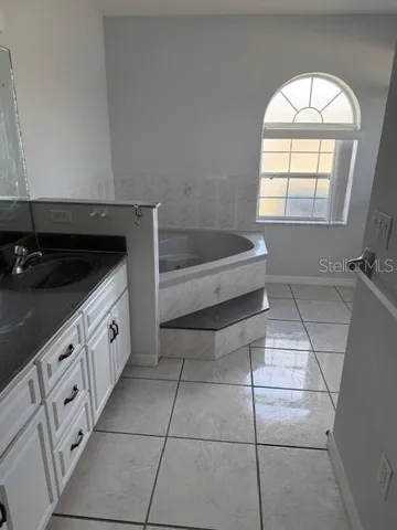 a spacious bathroom with a granite countertop sink a mirror and bathtub