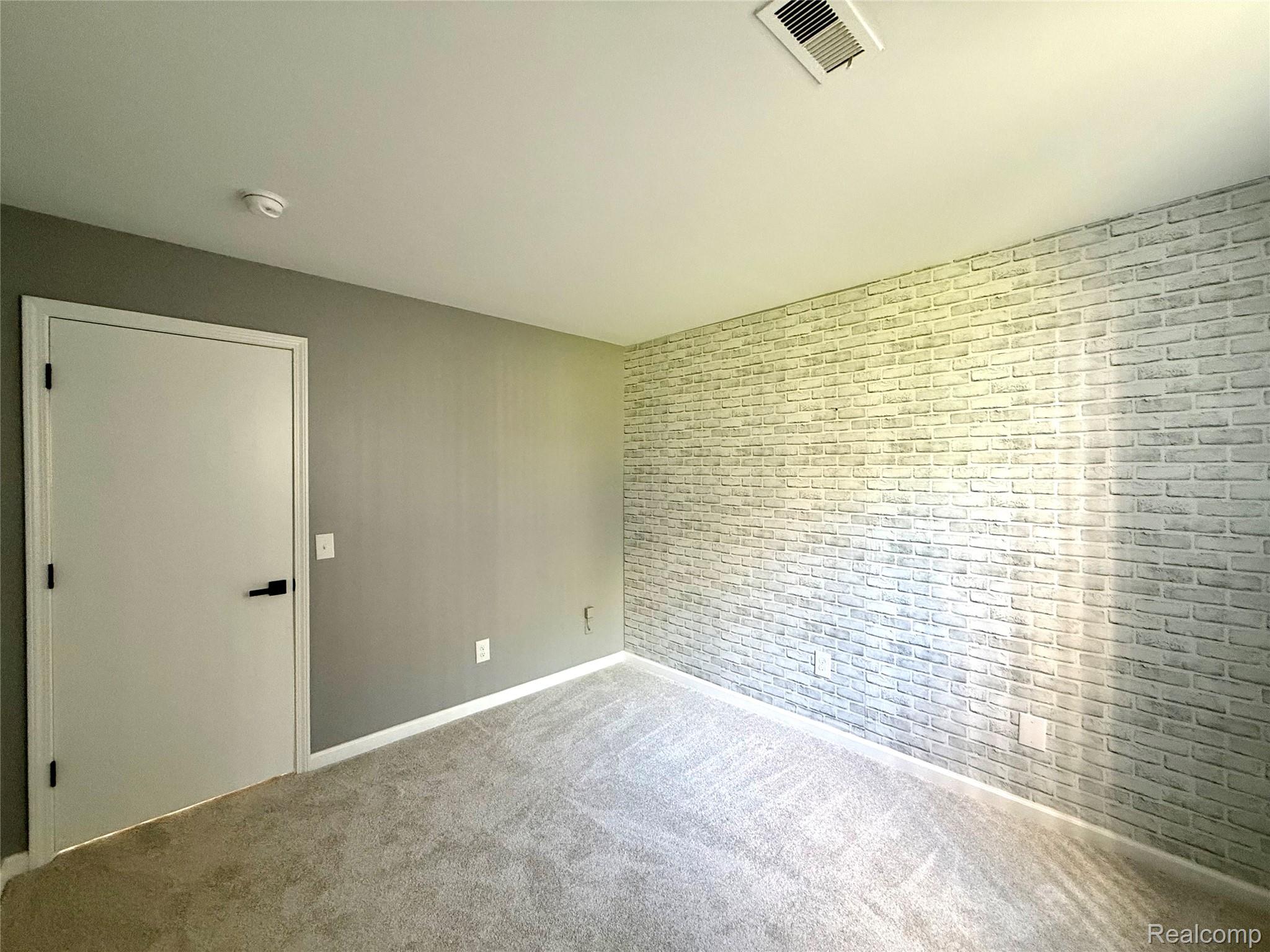 29870 West 12 Mile Road, Unit 703 Farmington, MI 48334 - Photo 23 of 40 Bedroom featuring a textured accent wall with a light-toned brick pattern