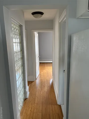 a view of a hallway with wooden floor and a bathroom