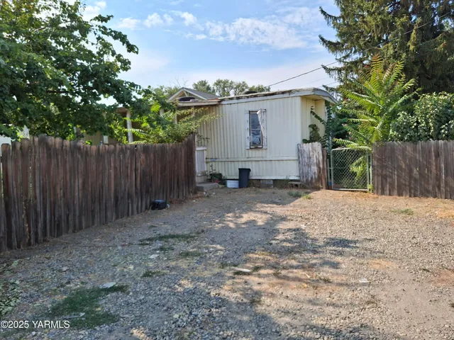 a backyard of a house with a tree and wooden fence