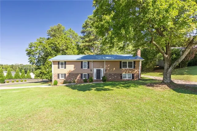 a view of a house with a big yard and large trees