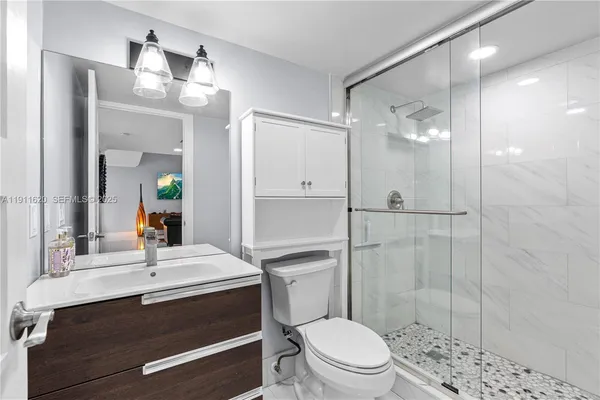 a bathroom with a sink a toilet a mirror and shower