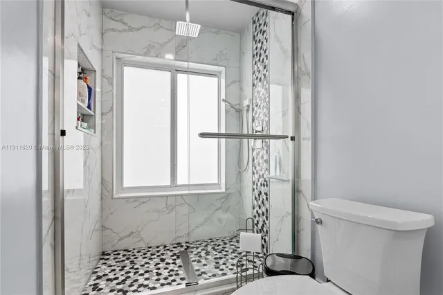 a bathroom with a toilet a window and shower