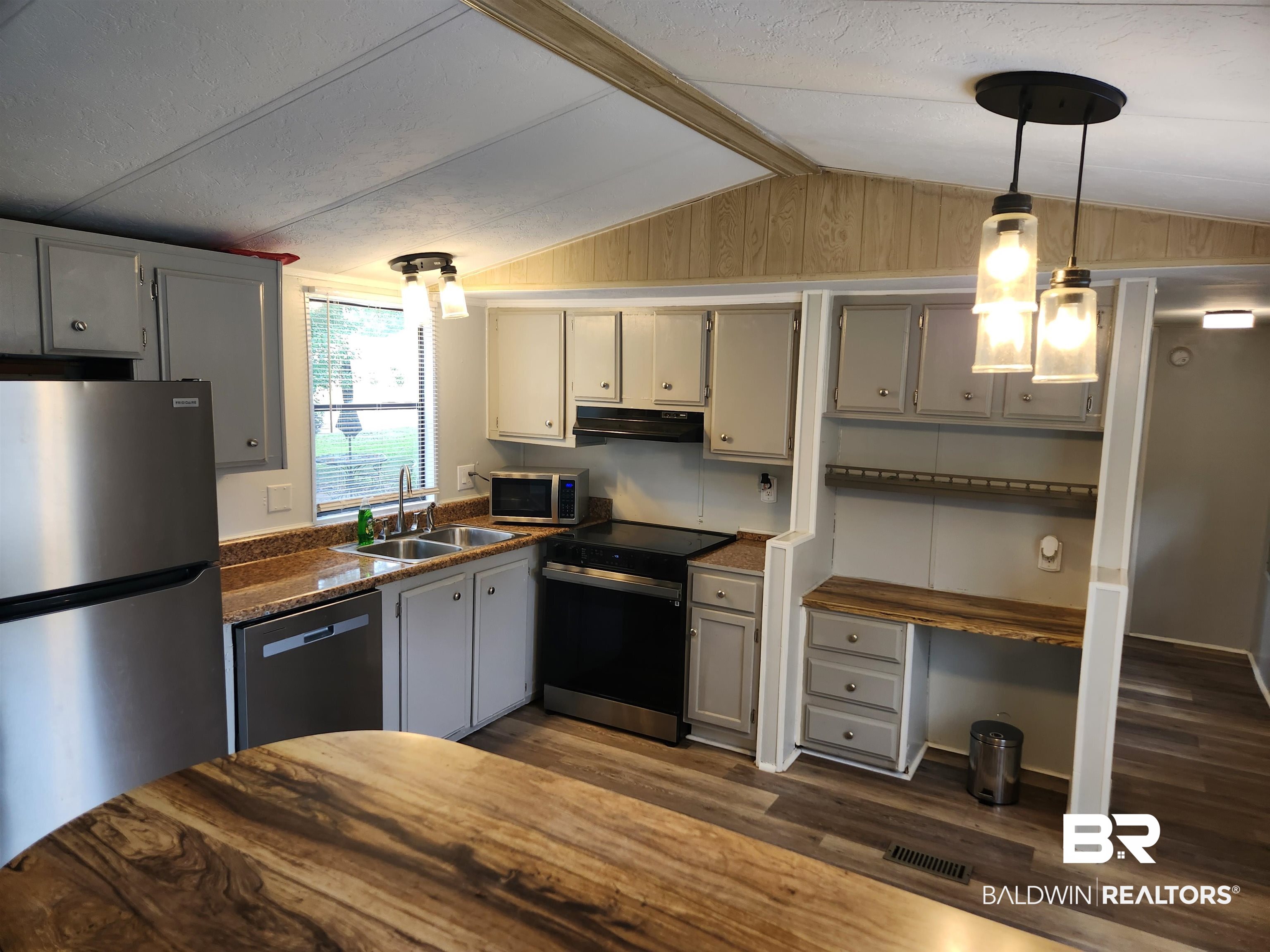 23051 Fritz Lane Foley, AL 36535 - Photo 18 of 26 Kitchen featuring stainless steel appliances, grey cabinetry, wood-finish flooring, a double basin sink, and a built-in desk area