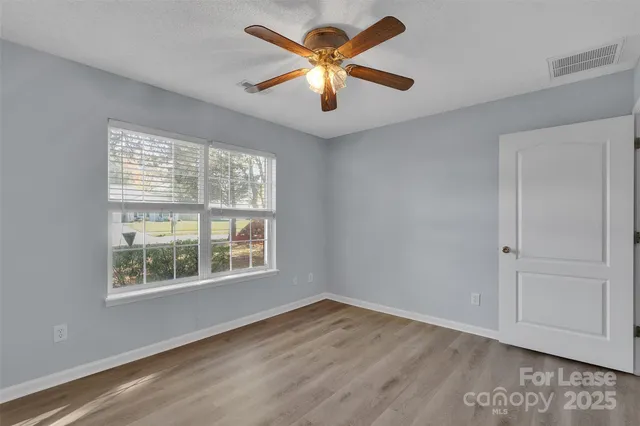 a view of an empty room with window and wooden floor