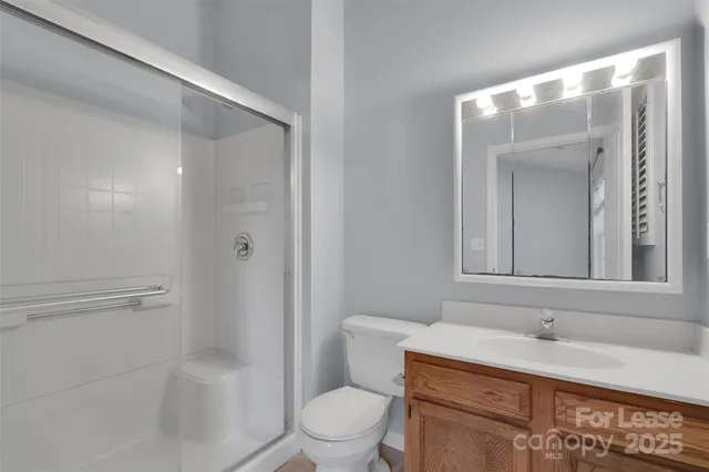 a bathroom with a granite countertop toilet a sink and a mirror