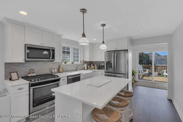 a kitchen with stainless steel appliances kitchen island granite countertop a stove a sink and a refrigerator