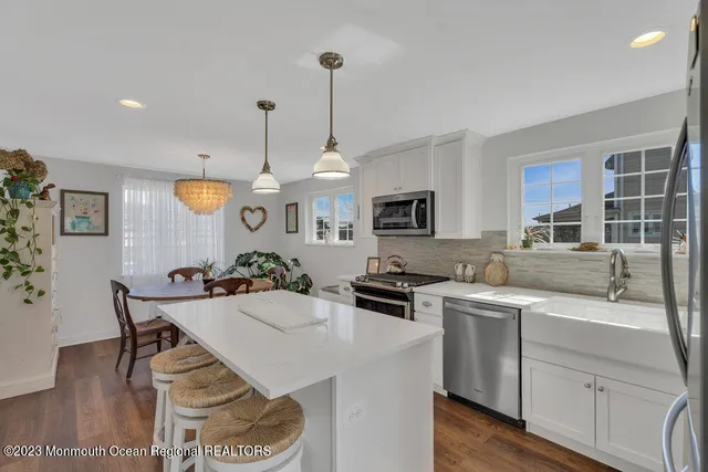 a kitchen with stainless steel appliances kitchen island granite countertop a sink a stove a dining table and chairs