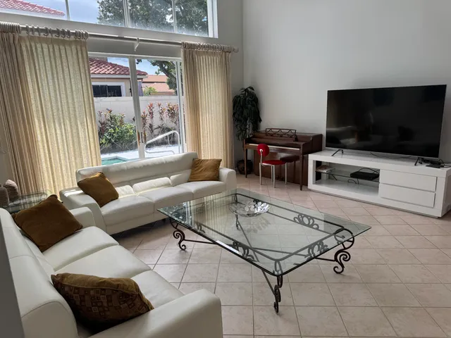a living room with furniture a flat screen tv and a window