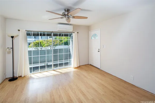 an empty room with wooden floor fan and windows
