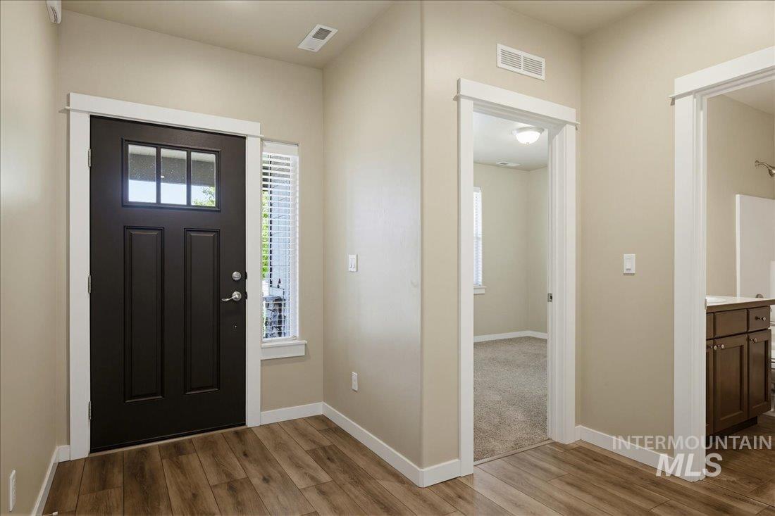 12460 West Azure Street Boise, ID 83713 - Photo 4 of 34 Entryway featuring a dark paneled door with glass inserts, a coordinating sidelight with horizontal blinds, and wood-finish flooring