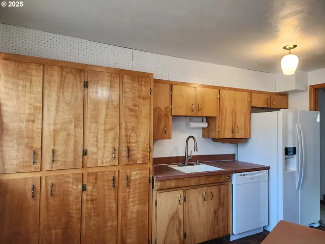 a kitchen with stainless steel appliances granite countertop a refrigerator a sink dishwasher and wooden cabinets with wooden floor