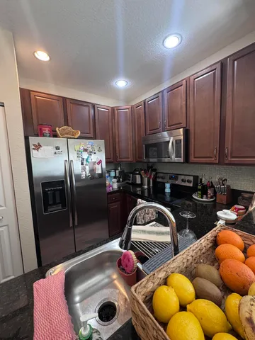 a kitchen with stainless steel appliances granite countertop a sink a stove and refrigerator