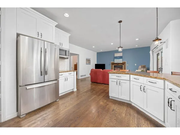 a kitchen with stainless steel appliances granite countertop a refrigerator sink and white cabinets