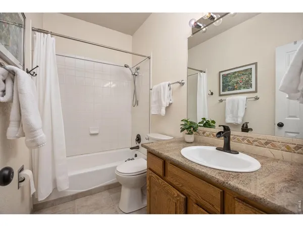 a bathroom with a granite countertop sink toilet a mirror a bathtub and shower