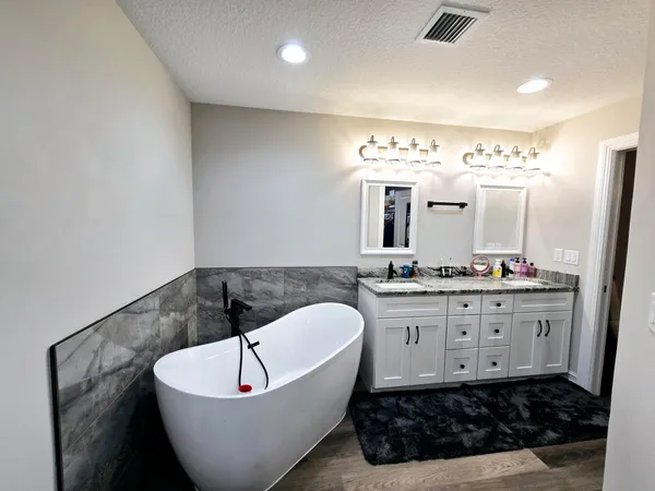 a spacious bathroom with a bathtub a sink and a mirror